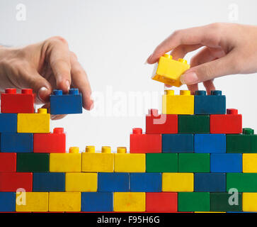 zwei Hände Teamarbeit Stack-up Lego set als Wand auf weißem Hintergrund Stockfoto