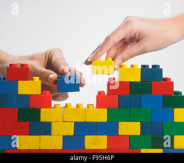 zwei Hände Teamarbeit Stack-up Lego set als Wand auf weißem Hintergrund Stockfoto