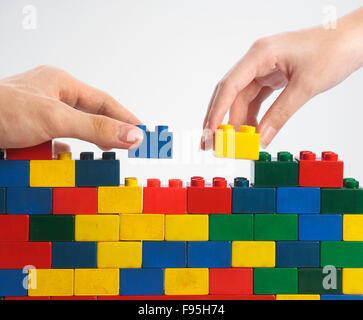 zwei Hände Teamarbeit Stack-up Lego set als Wand auf weißem Hintergrund Stockfoto