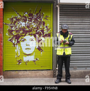 Street-Art durch Tankpetrol auf einen Auslöser an der Tib Street in der Innenstadt von Northern Quarter of Manchester, UK mit einem Traffic Warden Stockfoto