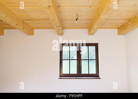 Leere unvollendete Zimmer mit weißen Wänden und Holzdecke in einem neu gebauten Haus Stockfoto