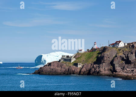 Fort Amherst Leuchtturm mit Blick auf einen Eisberg und einem kleinen Ausflugsboot. Der Leuchtturm befindet sich an der Mündung des The Narrows, ein Stockfoto