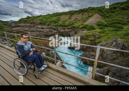 Mann im Rollstuhl auf der Aussichtsplattform, Hraunfossar, Borgarfjörður, Island Stockfoto