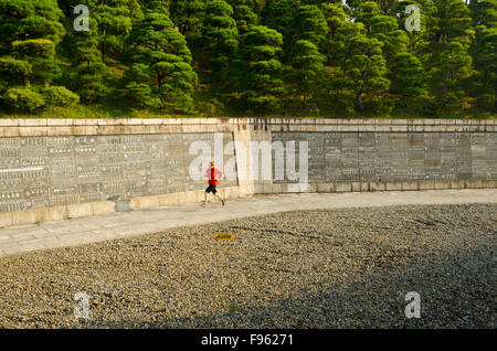 Eine Frau joggt vor einer Wand voller japanischen Schrift im Shinshoji Tempel in Narita, Japan Stockfoto