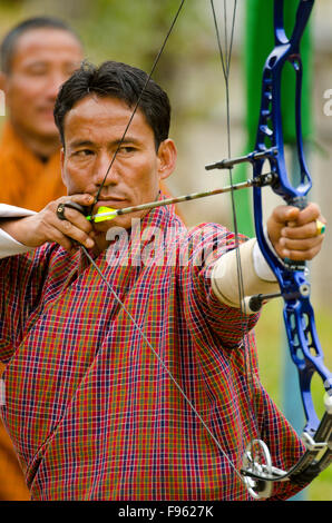 Ein buddhistische Mann zielt mit Pfeil und Bogen in Bhutan, wo der nationale Sport Bogenschießen ist Stockfoto