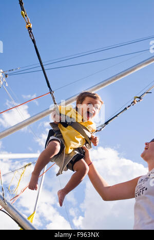 Ein Kleinkind kichert wie er auf einem Bungee-Trampolin in Whistler, BC prallte ist. Stockfoto