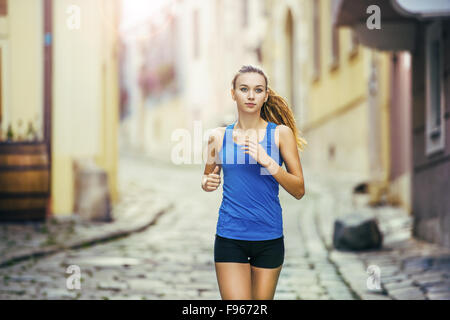 Junge weibliche Läufer ist auf gefliesten Pflaster Altstadt auf Center Joggen. Gesunde Lebensweise. Stockfoto