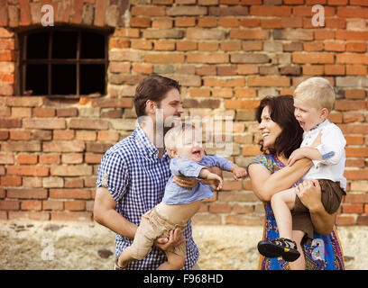 Glückliche junge Familie viel Spaß zusammen in der Natur durch das alte Backsteinhaus Stockfoto