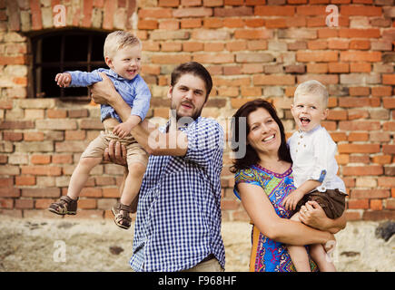 Glückliche junge Familie viel Spaß zusammen in der Natur durch das alte Backsteinhaus Stockfoto