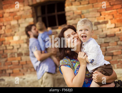 Glückliche junge Familie viel Spaß zusammen in der Natur durch das alte Backsteinhaus Stockfoto