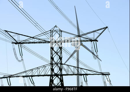 Macht Pylon und Wind Turbine gegen blauen Himmel Stockfoto