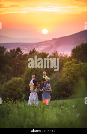 Glückliche junge Familie viel Spaß zusammen in der Natur bei Sonnenuntergang Feld Stockfoto