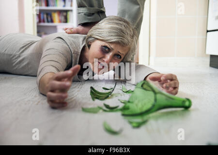 Frau Opfer von häuslicher Gewalt und Missbrauch. Reife Frau Angst eines Mannes mit zerbrochenen Flasche Stockfoto