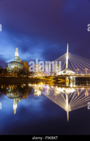 Skyline von Winnipeg mit Canadian Museum for Human Rights und Esplanade Riel Brücke nachts spiegelt sich in den Red River, Stockfoto