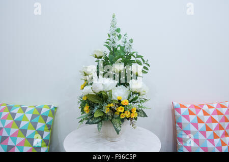 Künstliche Blumen Blumenstrauß in der Vase auf dem Tisch und paar Kissen Stockfoto