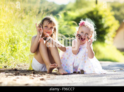 Zwei niedliche kleine Schwestern finalisieren und Tannenzapfen im Freien halten Stockfoto