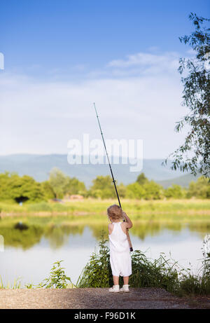 Niedliche kleine Mädchen auf dem See mit Fischen Stockfoto