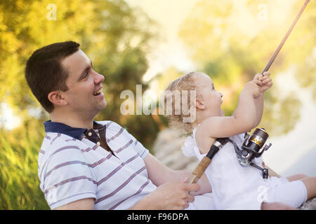 Glückliche junge Vater Angeln auf dem See mit seiner kleinen Tochter Stockfoto