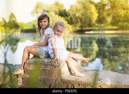 Zwei niedliche kleine Schwestern finalisieren am See Stockfoto