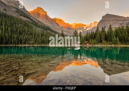 Lake O'Hara Lodge Gästekabinen und Gipfel spiegeln sich im ruhigen See bei Sonnenuntergang. Lake O'Hara, Yoho-Nationalpark, Brite/Britin Stockfoto