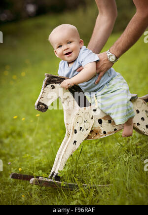 Niedliche kleine Junge auf das Schaukelpferd außerhalb Stockfoto