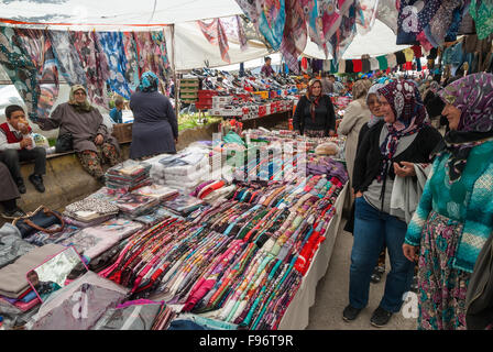 Zwei Frauen mit traditioneller Kleidung kaufen bunte Tücher auf dem offenen Markt der Stadt am 25. April 2014 in Ayvacik, Türkei. Stockfoto