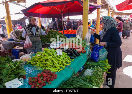 Eine Frau mit traditioneller Kleidung kauft Gemüse auf dem offenen Markt der Stadt am 25. April 2014 in Ayvacik, Türkei. Stockfoto