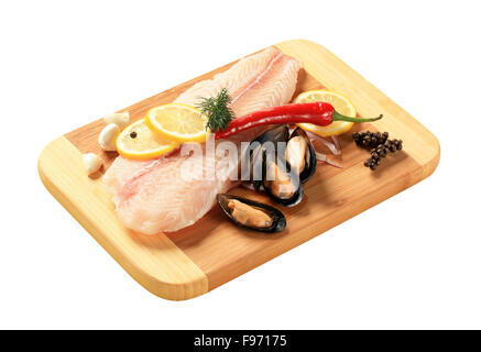 Frisches Fischfilet und Muscheln auf ein Schneidebrett Stockfoto