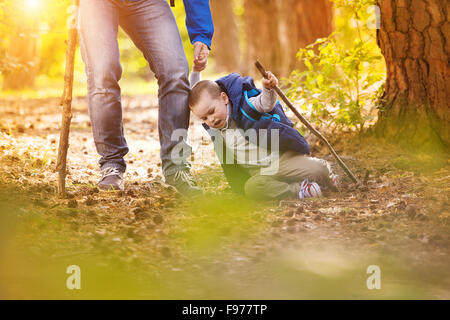 Kleiner Junge, Unfall beim Wandern im Wald mit seinem Vater. Stockfoto