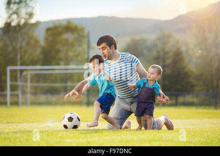 Junger Vater mit seiner kleinen Söhne Fußball spielen auf dem Fußballplatz Stockfoto