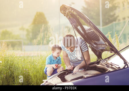 Junger Vater mit seinem kleinen Sohn Reparatur Auto Stockfoto