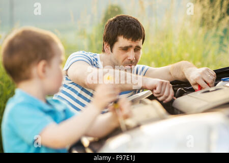 Junger Vater mit seinem kleinen Sohn Reparatur Auto Stockfoto