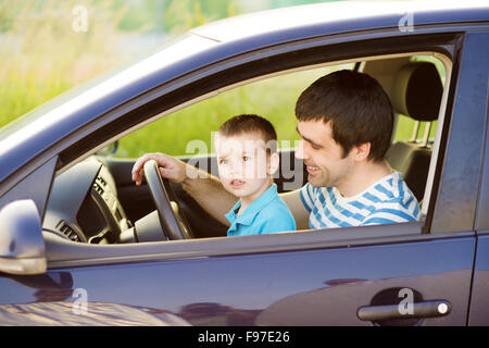 Junger Vater mit seinem kleinen Sohn zusammen Auto fahren Stockfoto