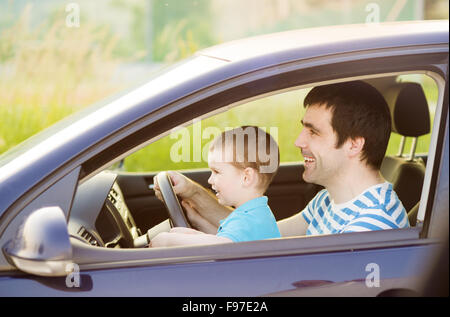 Junger Vater mit seinem kleinen Sohn zusammen Auto fahren Stockfoto