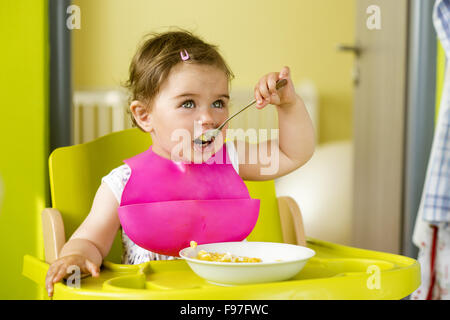 Kleines Mädchen im Hochstuhl ist Snack in der Küche Essen. Stockfoto