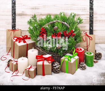 Weihnachts-Dekoration mit brennenden Kerzen und Geschenk-Box. Weihnachtsbaum-Niederlassungen in Korb Stockfoto