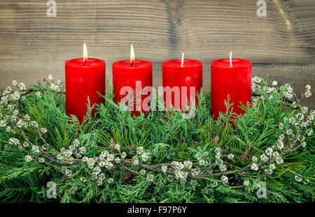 Advent Dekoration Tannenzweig mit roten brennenden Kerzen. Ferien-Hintergrund. Vintage-Stil getönten Bild Stockfoto