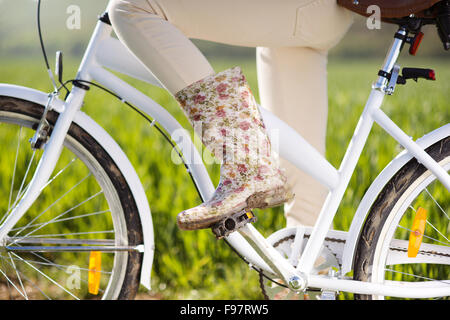 Detail der jungen Frau die Füße in Stiefeln Reiten auf Fahrrad im grünen Bereich Stockfoto