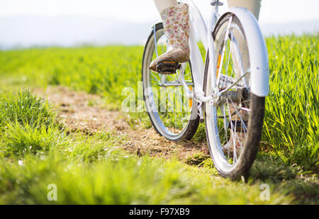 Detail der jungen Frau die Füße in Stiefeln Reiten auf Fahrrad im grünen Bereich Stockfoto