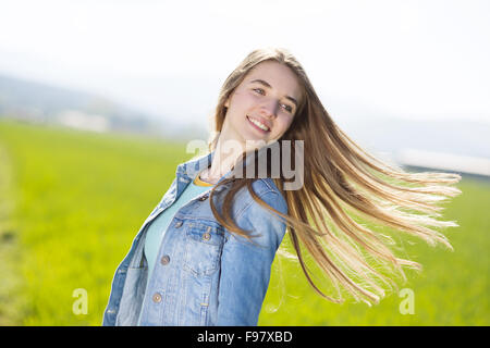 Fröhliches junges Mädchen in Blue Jeansjacke genießen freie Zeit im grünen Bereich Stockfoto