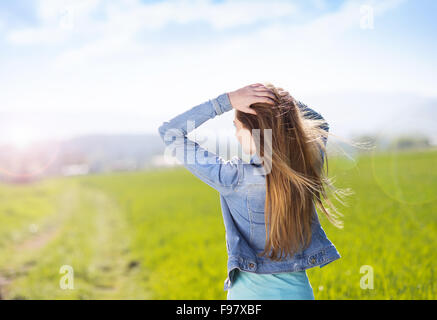 Fröhliches junges Mädchen in Blue Jeansjacke genießen freie Zeit im grünen Bereich Stockfoto