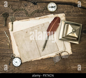 Antike Bürotechnik und Schreibwerkzeuge auf Schreibtisch aus Holz. Vintage Schlüssel, Uhr, Brille, Feder Stift, Kompass Stockfoto