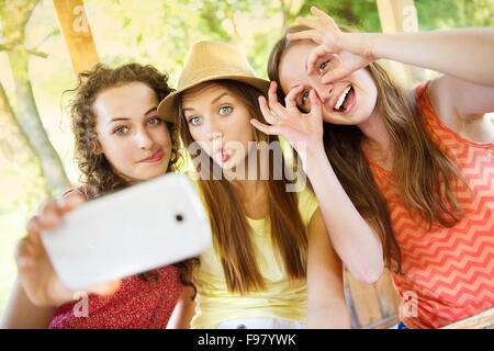 Drei schöne Mädchen trinken und nehmen Selfie mit Smartphone im Gastgarten Stockfoto