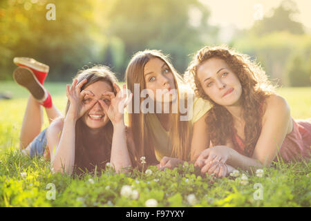 Drei schöne Mädchen gemeinsam lachen und auf dem Rasen im Freien in einem Park liegen. Stockfoto