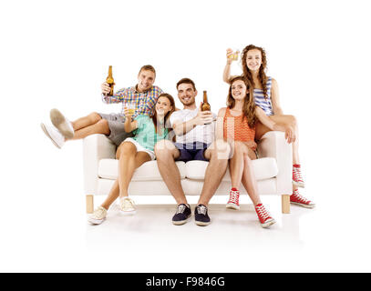 Gruppe der glückliche junge Menschen auf Sofa mit Getränke in Flaschen, isoliert auf weißem Hintergrund. Beste Freunde Stockfoto