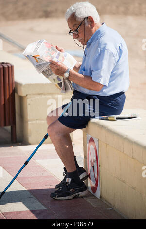 Elderley Mann der Lektüre Papier an Strandpromenade, Platja de S'Abanell, Blanes, Costa Brava, Provinz Girona, Katalonien, Spanien Stockfoto