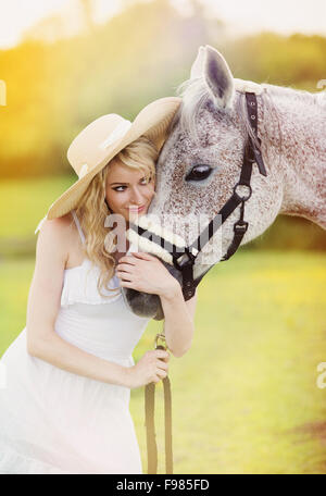 Frau im weißen Kleid mit Pferd in der grünen Landschaft wandern Stockfoto