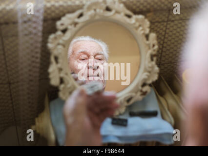 Senior woman rasieren Bart im Badezimmer vor dem Spiegel Stockfoto
