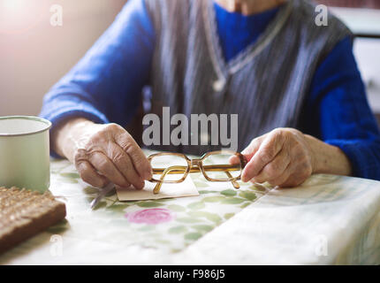 Alte Frau sitzt in ihrer Landhausküche Stockfoto