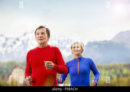 Älteres paar jogging Runde Tarn in wunderschöne Berge, Hügel und Hotel im Hintergrund Stockfoto
